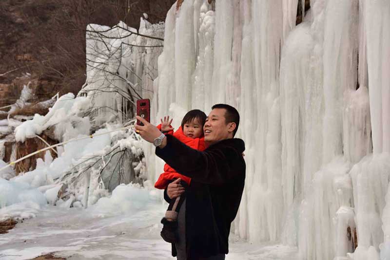 Un hombre se toma una foto junto a un ni?o en la monta?a Wuzhishan de Handan, provincia de Hebei, 15 de enero del 2019. [Foto: Yang Yanzhong/ Chinadaily.com.cn]
