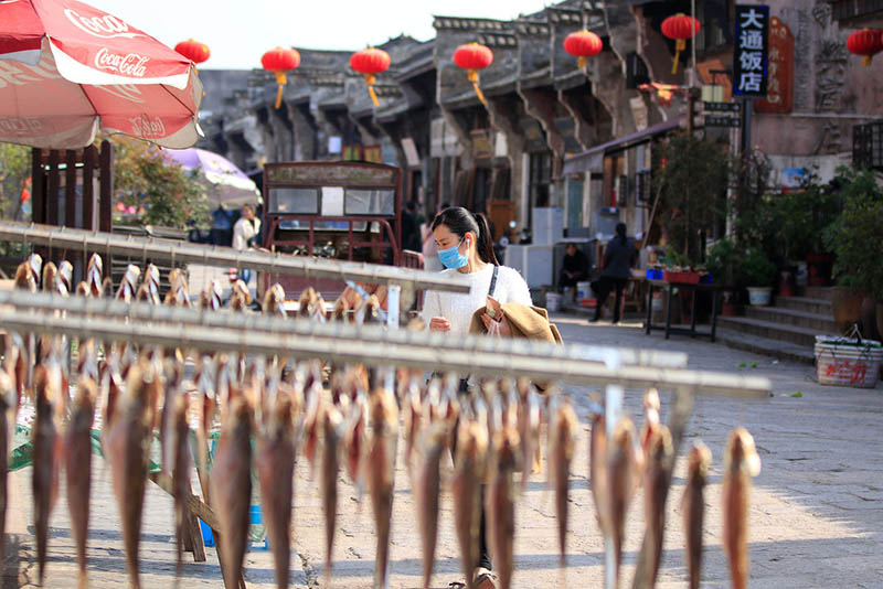 Una mujer mira el pescado seco en un puesto callejero en Datong, una antigua ciudad en la orilla oriental del río Yangtze en Tongling, provincia de Anhui, el 25 de marzo de 2019. [Foto de Zhu Lixin / chinadaily.com.cn]