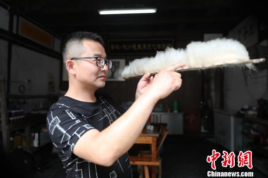 Jiang Guangming， un cocinero de este tipo de tofu, mide la longitud de los filamentos para determinar si el tofu ha fermentado completamente.[Foto: Fan Chengzhu/ Chinanews.com]