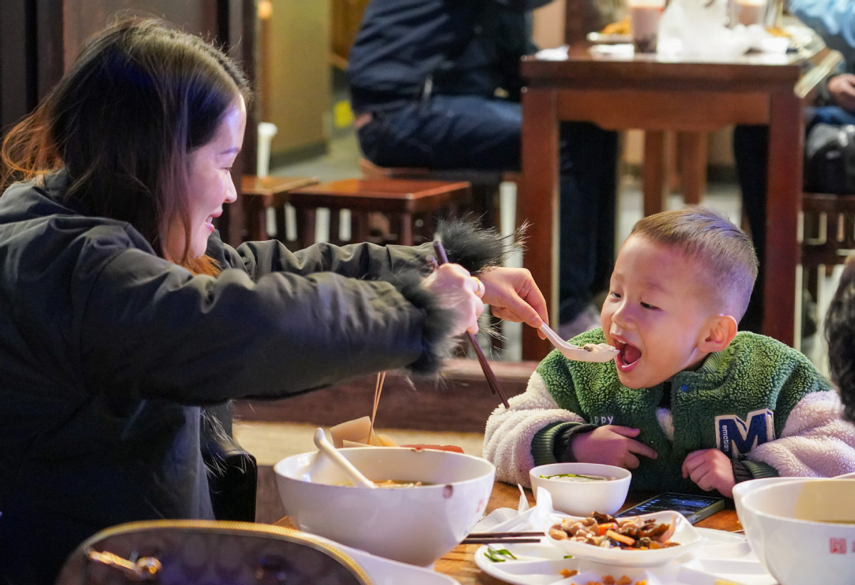 Turistas comen fideos de arroz por la noche en la ciudad de Kunming, provincia de Yunnan, 6 de diciembre del 2024. [Foto: Xinhua]