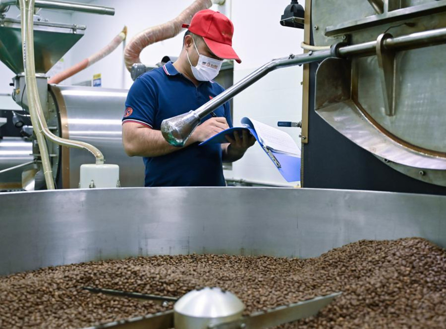 Un empleado trabaja en el taller de tostado de una empresa cafetalera en el distrito autónomo de las etnias li y miao de Qiongzhong, en la provincia sure?a china de Hainan, el 9 de enero de 2024. (Xinhua/Fan Yuqing)