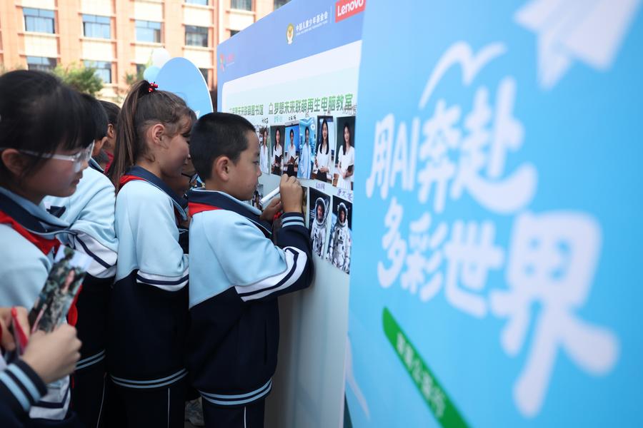 Un ni?o firma con su nombre en una imagen generada por IA de su profesión so?ada en la escuela Yanchuan del distrito de Zhangxian, ciudad de Dingxi, en la provincia noroccidental china de Gansu, el 10 de septiembre de 2025. (Xinhua/Chen Bin)