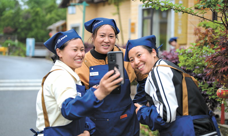 Tres mujeres practican las habilidades fotográficas que han aprendido en el Proyecto de Capacitación de Gerentes de Estancias Digital Mulan en la Prefectura Autónoma Tujia y Miao de Xiangxi, provincia de Hunan. (Foto: cortesía de la Fundación China para el Desarrollo Rural)